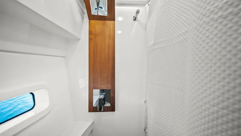 Slide: The Image of Modern Yacht Shower Area This sleek shower area on the 2025 Regal 38 EXC features a contemporary design with a wood accent panel and chrome fixtures. A window provides natural light and a serene view of the water, enhancing the luxurious experience. The minimalist design and high - 7180443