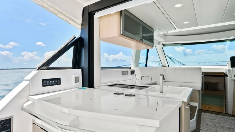 Slide: The Image of Sleek Galley with Outdoor View This modern galley aboard the 2025 Regal 38 EXC features sleek countertops and a double sink, offering both style and functionality. The expansive windows provide a panoramic view of the sea, enhancing the open, airy feel of the space. Elegant cabinetry a - 7180416