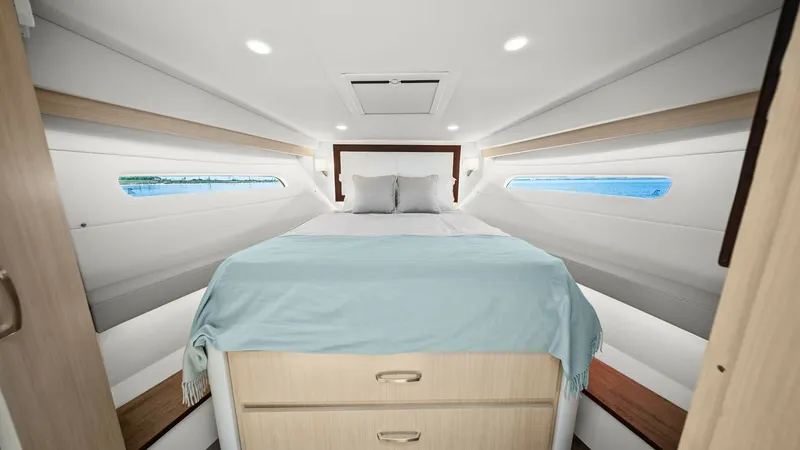 Slide: The Image of Forward Cabin with Queen Berth The forward cabin of the 2025 Regal 38 EXC features a spacious queen-sized berth, providing ample comfort for overnight stays. Elegant wood accents and soft ambient lighting create a cozy and inviting atmosphere. Large side windows allow natural light to - 7180415