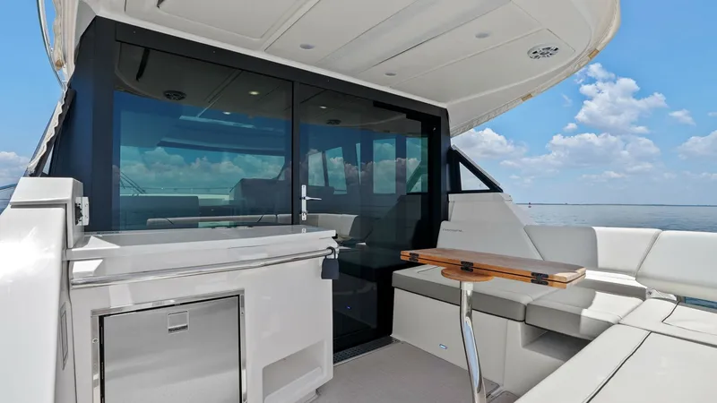 Slide: The Image of Aft Deck with Seating and Bar The aft deck of the 2025 Regal 38 EXC offers a luxurious outdoor space with plush seating and a sleek bar area. The ample seating arrangement is complemented by a polished wooden table, perfect for entertaining guests while enjoying panoramic ocean views. - 7180423