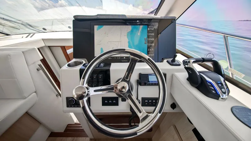 Slide: The Image of Helm Station with Navigation Display The helm station of the 2025 Regal 38 EXC offers a sleek and modern design, featuring an advanced navigation display for precise control. The stainless steel steering wheel complements the ergonomic layout, ensuring comfortable handling. Premium finishes - 7180412