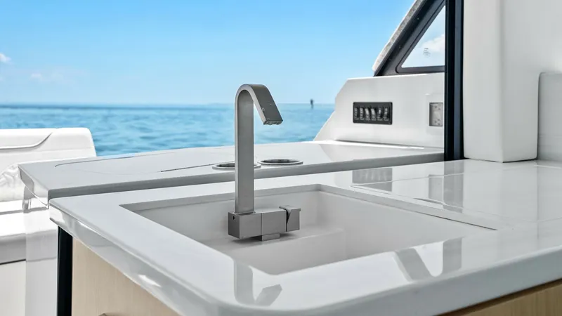 Slide: The Image of Sleek Cockpit Wet Bar This image showcases the modern wet bar in the cockpit of the 2025 Regal 38 EXC. Featuring a streamlined faucet and a polished countertop, the design emphasizes both functionality and elegance. The view of the open ocean adds an inviting backdrop, perfect - 7180428