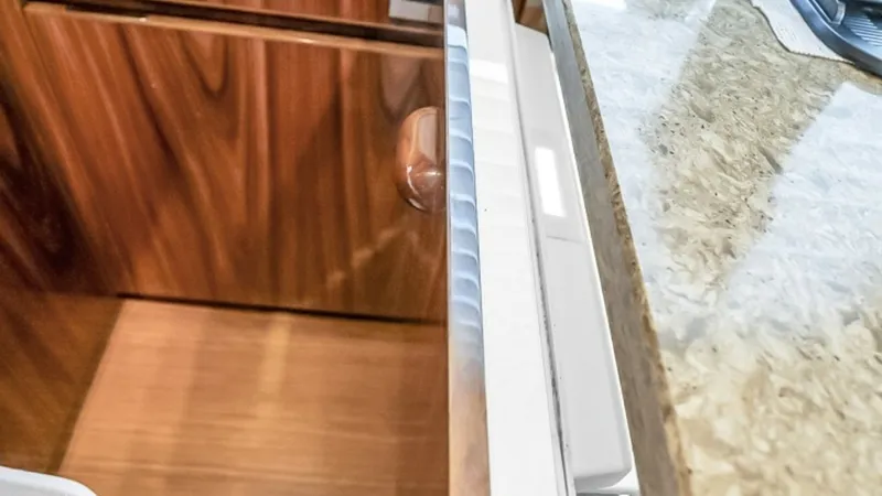 Slide: The Image of Galley Storage Drawer This image showcases a sleek, pull-out storage drawer in the galley of the 2021 Viking 48 Convertible. The design features high-quality wood finishes and a smooth countertop, adding both elegance and functionality to the space. The efficient layout maximi - 7224860