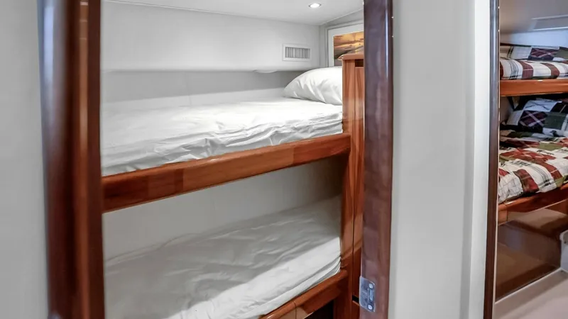 Slide: The Image of Guest Stateroom with Twin Bunks This cozy guest stateroom features twin bunk beds, perfect for accommodating additional guests. The space is well-lit with recessed lighting, enhancing the warm wood finishes. Its compact design ensures comfort and privacy, making it ideal for extended vo - 7224883