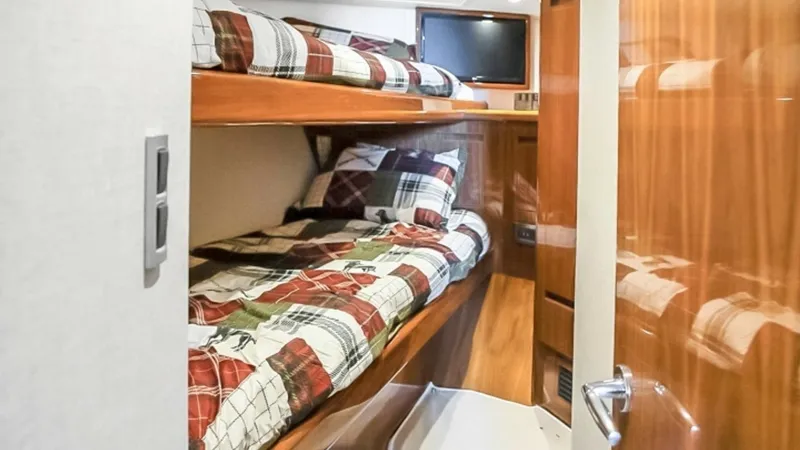 Slide: The Image of Guest Cabin with Bunk Beds This cozy guest cabin features stylish bunk beds with plaid bedding, perfect for accommodating additional passengers. The warm wood finishes and ample lighting create a welcoming atmosphere, while the compact layout maximizes space efficiency. Ideal for o - 7224876