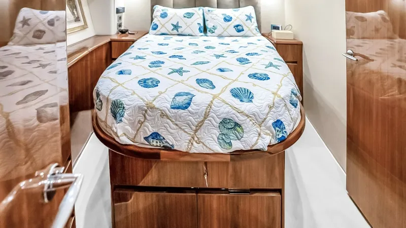 Slide: The Image of Guest Stateroom with Double Berth The guest stateroom features a comfortable double berth adorned with a nautical-themed quilt, set against a backdrop of warm wood finishes. Ample storage is provided beneath the bed, while soft overhead lighting creates a cozy atmosphere. The cabin's eleg - 7224867