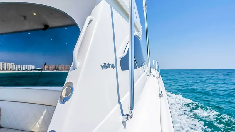 Slide: The Image of Starboard Side View with Ocean Backdrop This image showcases the sleek starboard side of the 2021 Viking 48 Convertible, highlighting its smooth lines and polished finish. The expansive windows offer a glimpse into the luxurious interior, while the vessel cruises through the sparkling ocean wat - 7224891
