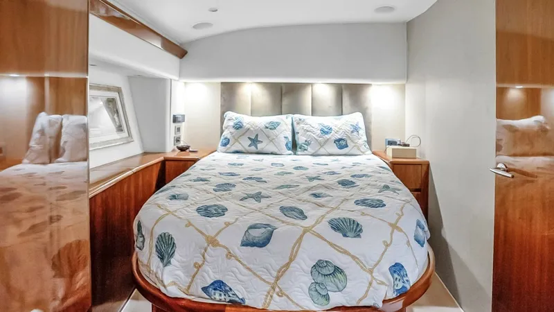 Slide: The Image of Luxurious Forward Stateroom Experience comfort in the forward stateroom featuring a plush, queen-sized berth adorned with ocean-themed bedding. The space is enhanced by elegant wood finishes and ample storage, creating a warm and inviting atmosphere. Recessed lighting and contempora - 7224868