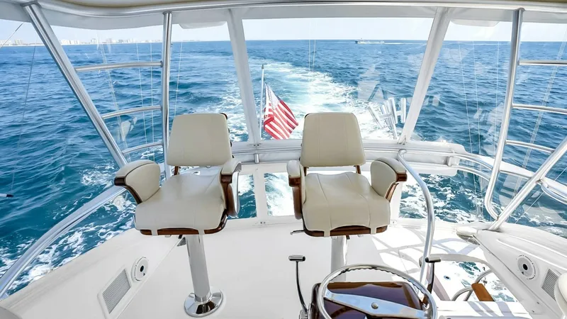 Slide: The Image of Flybridge Helm Station The flybridge helm station on the 2021 Viking 48 Convertible offers commanding views and advanced navigational controls. Two plush captain's chairs provide comfort, while the polished wooden wheel adds a touch of elegance. Large windows surround the area, - 7224896