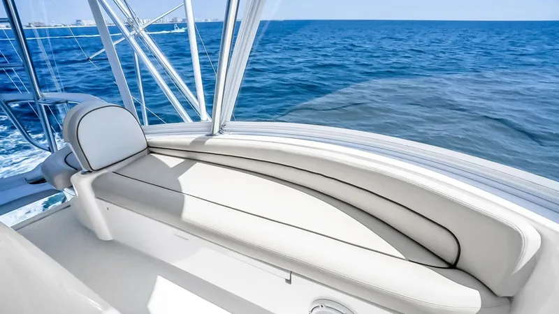 Slide: The Image of Flybridge Forward Seating The Viking 48 Convertible's flybridge features luxurious forward seating with plush white upholstery, offering a comfortable space to enjoy panoramic ocean views. The sleek design is complemented by sturdy stainless steel railings and expansive windows, e - 7224904