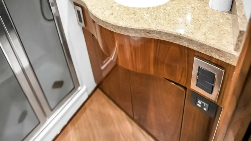Slide: The Image of Luxury Bathroom Vanity Area This elegant bathroom vanity showcases a polished stone countertop paired with rich wooden cabinetry, demonstrating the high-quality craftsmanship of the Viking 48 Convertible. The integrated sink and modern fixtures add a touch of sophistication, while t - 7224874