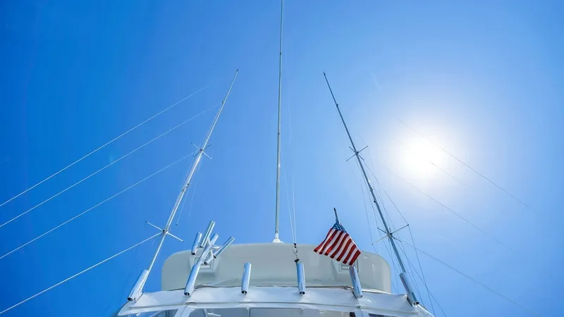 Slide: The Image of Viking 48 Convertible Tower View This image captures the impressive tower of the 2021 Viking 48 Convertible, showcasing its sleek lines against a clear blue sky. The tower features an array of antennas and a prominent flag, highlighting its readiness for offshore adventures. The design e - 7224895