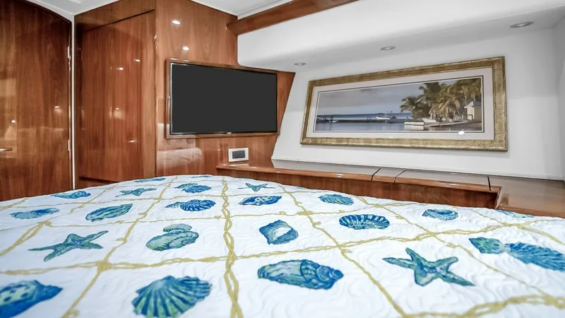 Slide: The Image of Luxurious Master Stateroom Interior The master stateroom of the 2021 Viking 48 Convertible exudes elegance with its rich wood finishes and modern amenities. A large, flat-screen TV is seamlessly integrated into the space, while the plush bedding features a nautical theme with vibrant shell - 7224870