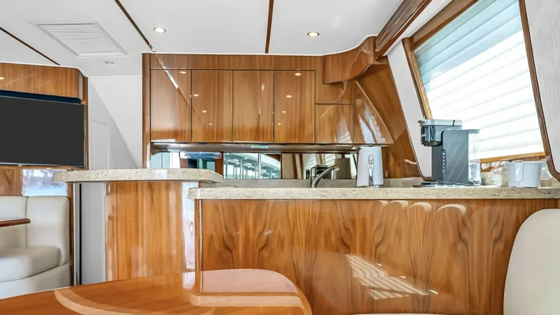 Slide: The Image of Galley and Dining Area Interior The galley of the 2021 Viking 48 Convertible showcases elegant wood cabinetry and modern appliances, providing both functionality and style. The polished countertop and integrated seating offer a convenient dining space, ideal for entertaining. Large wind - 7224854