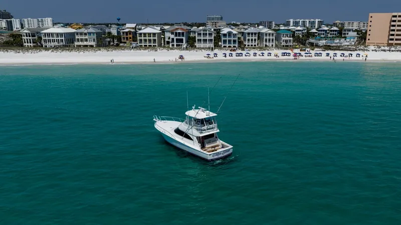 Slide: The Image of Aerial View of Convertible Yacht This image showcases the Viking 48 Convertible yacht, 'High Impact,' gracefully anchored near a scenic shoreline. The vessel's sleek design and flybridge are prominently featured, highlighting its superior craftsmanship and spacious layout. The vibrant tu - 7224928