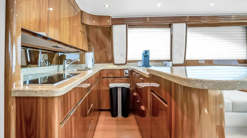 Slide: The Image of Galley with Modern Amenities This well-appointed galley on the 2021 Viking 48 Convertible features elegant wood finishes and sleek countertops, offering ample space for meal preparation. The area is equipped with modern appliances and under-cabinet lighting, enhancing both functional - 7224863