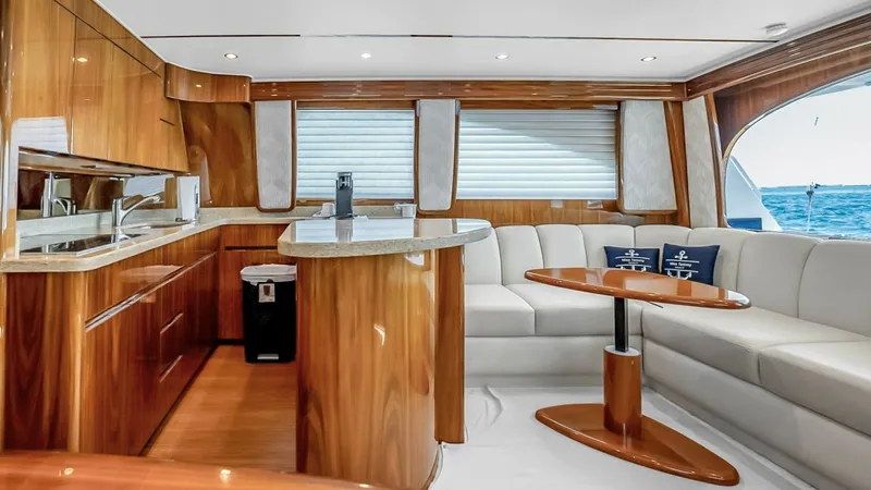 Slide: The Image of Elegant Interior Salon with Galley The salon of the 2021 Viking 48 Convertible features a luxurious blend of high-gloss wood finishes and plush seating, creating a warm and inviting atmosphere. The open layout seamlessly integrates the galley, equipped with modern appliances and ample stor - 7224858