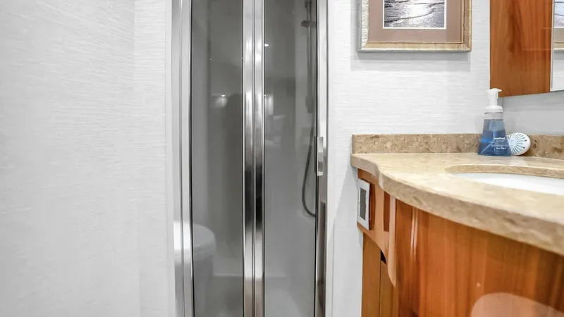 Slide: The Image of Elegant Ensuite Bathroom This stylish ensuite bathroom on the Viking 48 Convertible features a sleek glass-enclosed shower, offering both functionality and a modern aesthetic. The vanity showcases polished wood cabinetry complemented by a smooth countertop, providing ample space - 7224872