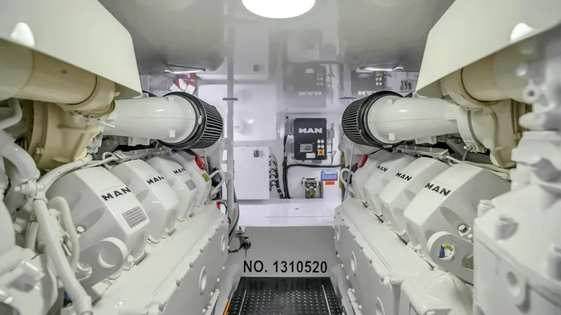 Slide: The Image of Engine Room with Twin MAN Engines This image showcases the pristine engine room of the Viking 48 Convertible, featuring twin MAN engines. The layout is meticulously organized for optimal performance, with polished surfaces and easy access to key components. The bright lighting and clean d - 7224906
