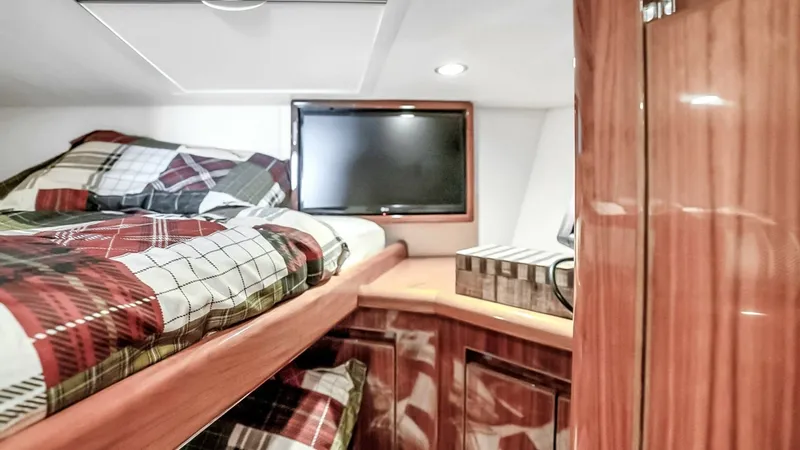 Slide: The Image of Guest Cabin with Bunk Beds This cozy guest cabin on the Viking 48 Convertible features comfortable bunk beds adorned with plaid bedding. The warm wood finishes and built-in storage create a welcoming atmosphere. A mounted flat-screen TV adds modern convenience for entertainment dur - 7224875