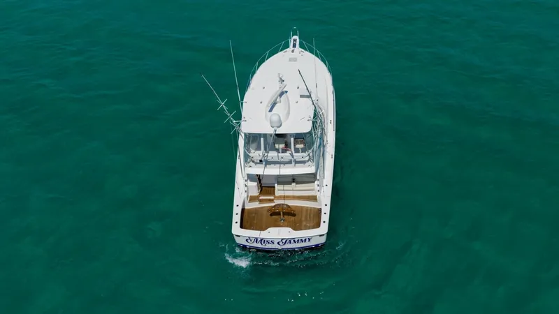 Slide: The Image of Aerial View of Aft Deck This aerial shot showcases the spacious aft deck of the 2021 Viking 48 Convertible, 'High Impact'. The deck is designed for both relaxation and functionality, featuring ample seating and a robust fishing setup. The teak flooring adds a touch of elegance, - 7224929