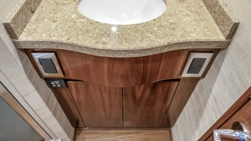 Slide: The Image of Elegant Vanity in Guest Head The guest head of the 2021 Viking 48 Convertible features a stylish vanity with a polished stone countertop and a modern stainless steel faucet. The sleek cabinetry provides ample storage, complemented by the warm wood finishes that add a touch of luxury. - 7224880