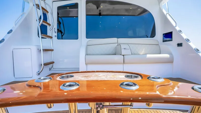 Slide: The Image of Aft Deck with Teak Table The aft deck of the 2021 Viking 48 Convertible features a beautifully crafted teak table with integrated cup holders, perfect for entertaining. The plush seating area offers comfort and style, accented by elegant upholstery and a sleek design. The ladder - 7224884