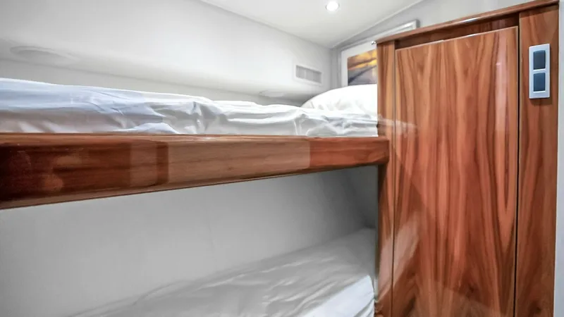 Slide: The Image of Guest Cabin with Bunk Beds This guest cabin on the Viking 48 Convertible offers comfortable bunk-style sleeping arrangements, ideal for accommodating additional guests. The rich wood finishes add a touch of elegance and warmth to the space, while the soft lighting creates a cozy am - 7224882