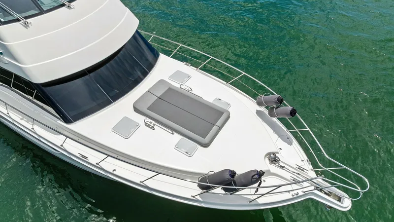 Slide: The Image of Foredeck with Sunpad and Railings The foredeck of the 2021 Riviera 57 Enclosed Bridge features a spacious sunpad, perfect for lounging while enjoying the ocean views. The sleek design is complemented by stainless steel railings and strategically placed hatches for easy access and ventilat - 7541542