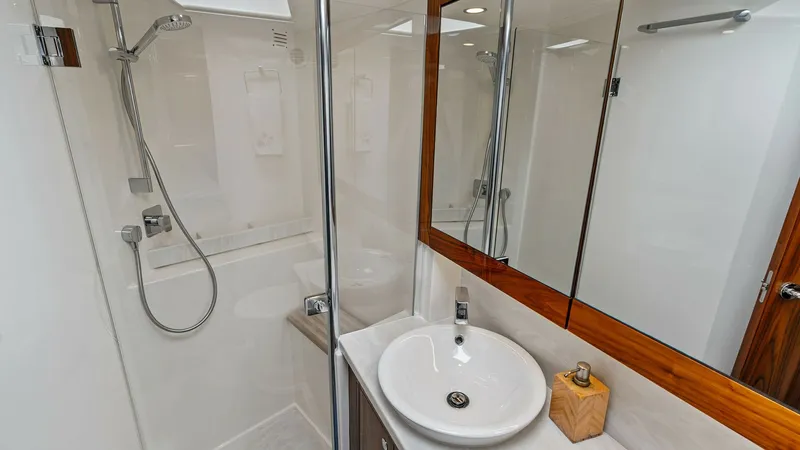 Slide: The Image of Elegant Enclosed Bridge Bathroom This sophisticated bathroom on the 2021 Riviera 57 Enclosed Bridge features a sleek shower with modern fixtures and a streamlined glass door. The elegant vanity is topped with a polished surface, complemented by a stylish vessel sink and mirrored cabinetr - 7541516