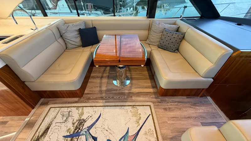 Slide: The Image of Salon Seating Area with Table This inviting salon seating area on the 2021 Riviera 57 Enclosed Bridge features plush, wraparound leather seating and a beautifully crafted wooden table. The space is accented with elegant throw pillows, creating a cozy and stylish atmosphere for relaxat - 7396144