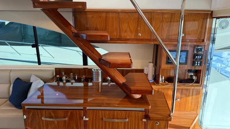 Slide: The Image of Elegant Interior Staircase and Bar This image showcases the luxurious staircase leading to the enclosed bridge of the 2021 Riviera 57. The rich wood finish complements the sleek cabinetry, creating an inviting atmosphere. The built-in bar area offers a stylish space for entertaining, compl - 7396139