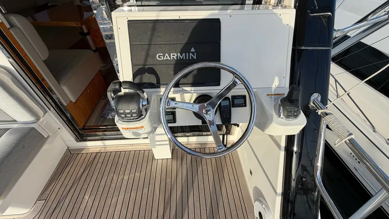 Slide: The Image of Flybridge Helm Station with Garmin Display The flybridge helm station of the 2021 Riviera 57 Enclosed Bridge features a modern steering wheel and advanced Garmin navigation display, ensuring precise control and navigation. The teak decking adds a touch of elegance, complementing the sleek, functio - 7396130