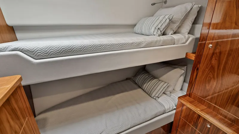 Slide: The Image of Guest Cabin with Bunk Beds The guest cabin features comfortable bunk beds, perfect for accommodating additional guests on board. The space is elegantly designed with quality bedding and warm wood finishes, creating a cozy and inviting atmosphere. Storage cabinets add functionality, - 7541513