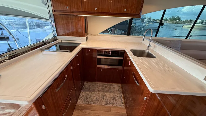 Slide: The Image of Galley with Modern Appliances The galley of the 2021 Riviera 57 Enclosed Bridge features sleek countertops and high-quality wooden cabinetry, offering a luxurious culinary space. Equipped with state-of-the-art appliances, including a built-in oven and stovetop, this area is designed f - 7396137