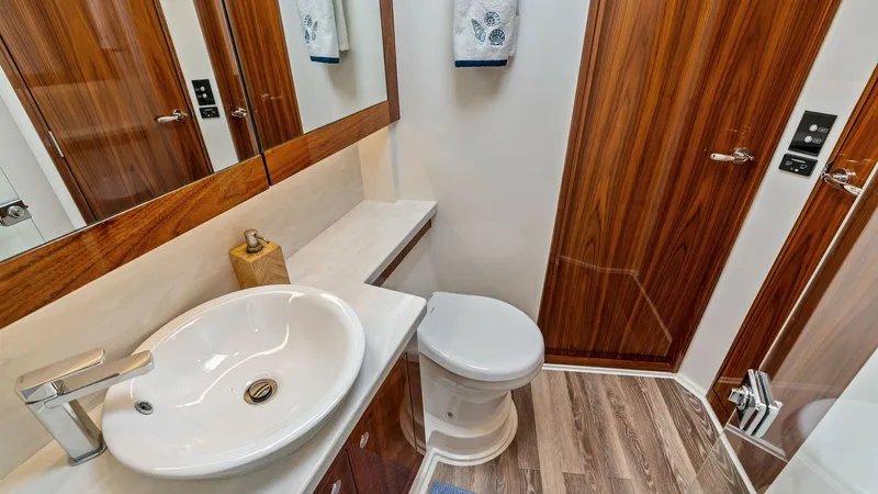 Slide: The Image of Luxury Guest Bathroom This elegant guest bathroom aboard the 2021 Riviera 57 Enclosed Bridge features a sleek, modern design with high-gloss wood finishes and a contemporary basin sink. The room is well-appointed with a large mirror and ample storage, complemented by stylish c - 7541520