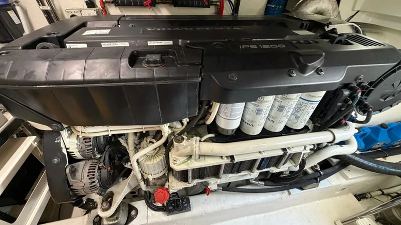 Slide: The Image of Engine Room with IPS 1200 Engine The image showcases the engine room of the 2021 Riviera 57 Enclosed Bridge, featuring a powerful IPS 1200 engine. The space is meticulously organized, with essential components like filters and wiring easily accessible for maintenance. The clean and well- - 7396154