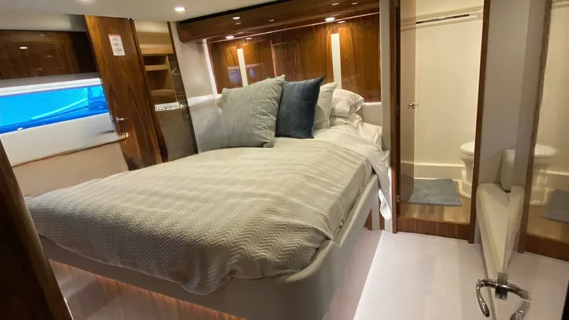 Slide: The Image of Guest Stateroom with Ensuite Bathroom The guest stateroom of the 2021 Riviera 57 Enclosed Bridge offers a luxurious retreat with a spacious berth and elegant wood finishes. Soft lighting and plush bedding create a warm, inviting ambiance. The ensuite bathroom features modern fixtures and a sl - 7396150