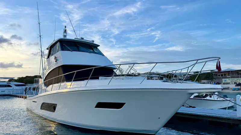 Slide: The Image of Starboard Bow View at Dock This image showcases the sleek, modern design of the 2021 Riviera 57 Enclosed Bridge from a starboard bow perspective. The vessel's streamlined hull and expansive windows emphasize its luxurious appeal, while the enclosed bridge offers a commanding view. - 7396159
