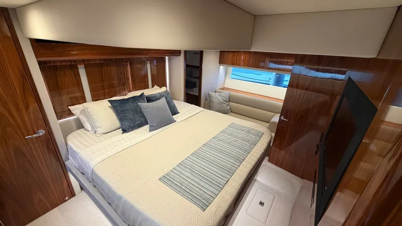 Slide: The Image of Luxurious Master Stateroom This elegant master stateroom features a plush double bed with high-quality linens and decorative cushions. The room is adorned with rich wood finishes and a large window providing ample natural light. A built-in flat screen TV and comfortable seating enh - 7396145
