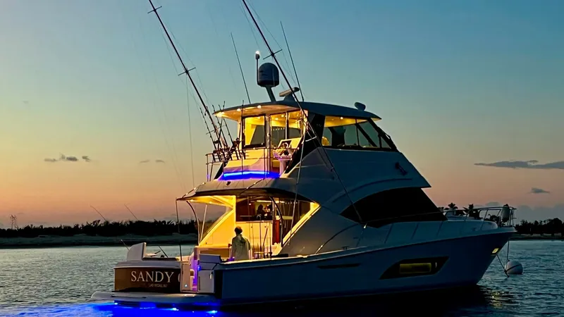 Slide: The Image of Aft Deck at Sunset The 2021 Riviera 57 Enclosed Bridge is beautifully captured at sunset, showcasing its elegant aft deck. The yacht is illuminated with ambient lighting, creating a warm and inviting atmosphere. The spacious design and sleek lines are complemented by the gl - 7396160