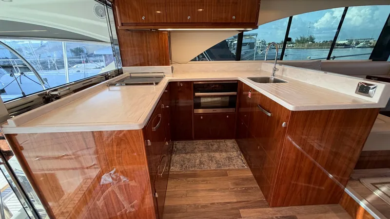 Slide: The Image of Galley with Modern Appliances The galley on the 2021 Riviera 57 Enclosed Bridge features sleek, high-gloss cabinetry and expansive countertops, offering ample space for meal preparation. Equipped with state-of-the-art appliances, including an oven and sink, this area combines function - 7396133