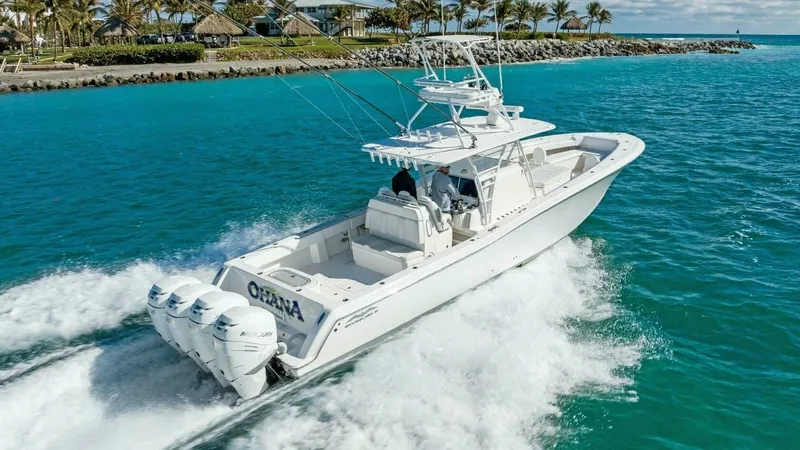 Slide: The Image of Aerial View of Ohana in Motion This striking aerial shot captures the 2019 Invincible 42 Open Fisherman, 'Ohana,' slicing through the vibrant turquoise waters. Equipped with powerful quad outboard engines, the vessel demonstrates impressive speed and agility. The spacious deck layout i - 7285541