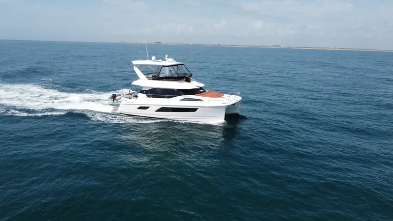 Slide: The Image of Aquila 44 CAT Cruising Side View The 2021 Aquila 44 CAT 'Hey Beautiful' gracefully navigates open waters, showcasing its sleek and modern design. The flybridge offers commanding views, while the expansive windows along the hull promise ample natural light inside. With its robust twin hul - 7414011