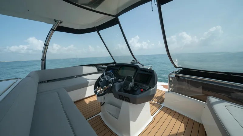 Slide: The Image of Flybridge Helm with Panoramic Views The flybridge helm of the 2021 Aquila 44 CAT offers a commanding view with its expansive, wrap-around windows. It features a sophisticated navigation console equipped with modern controls and a plush seating area, perfect for enjoying the open sea. The te - 7413983