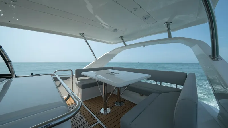 Slide: The Image of Aquila 44 CAT Aft Deck Lounge The aft deck of the 2021 Aquila 44 CAT features a spacious seating area with plush, gray upholstered benches surrounding a sleek dining table. The teak flooring adds a touch of elegance, while the open design offers expansive ocean views, perfect for alfr - 7413980