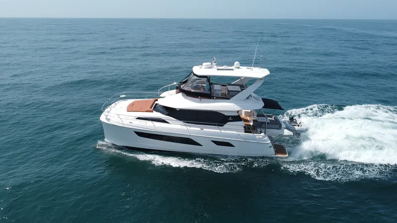 Slide: The Image of Aerial View of Aquila 44 CAT This aerial image showcases the sleek design of the 2021 Aquila 44 CAT, 'Hey Beautiful,' cruising effortlessly through open waters. The vessel features a spacious flybridge with ample seating and a helm station, providing panoramic views. The aft deck off - 7414024