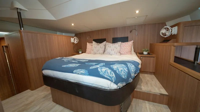 Slide: The Image of Master Stateroom with Elevated Bed The master stateroom of the 2021 Aquila 44 CAT features a luxurious elevated bed, accentuated by rich wooden finishes and soft ambient lighting. The spacious layout includes stylish bedside tables and contemporary reading lamps, creating a cozy and inviti - 7413970