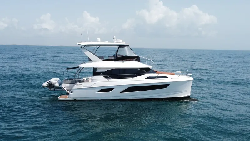 Slide: The Image of Side Profile of Aquila 44 CAT This image showcases the sleek side profile of the 2021 Aquila 44 CAT, 'Hey Beautiful'. The vessel's modern design features expansive windows for panoramic views, enhancing the luxurious cruising experience. Notable elements include the spacious flybridge - 7414031