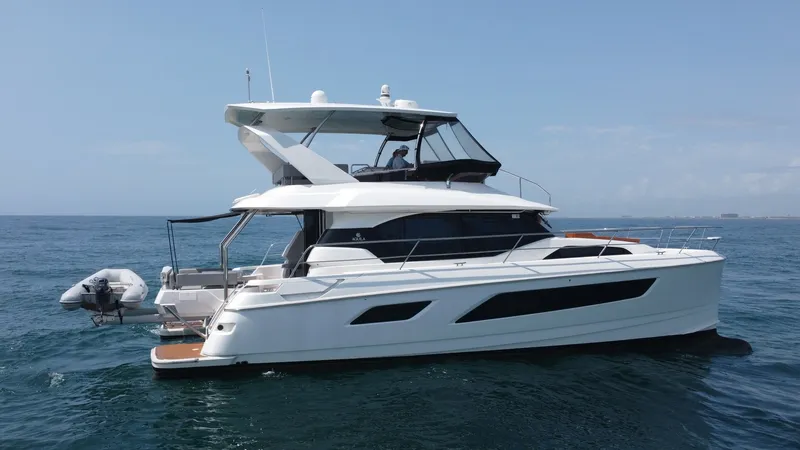Slide: The Image of Starboard View of Aquila 44 CAT This image showcases the sleek starboard side of the 2021 Aquila 44 CAT, highlighting its modern design and spacious flybridge. The yacht features expansive windows, offering panoramic views and natural light throughout the interior. Notable is the aft de - 7414040